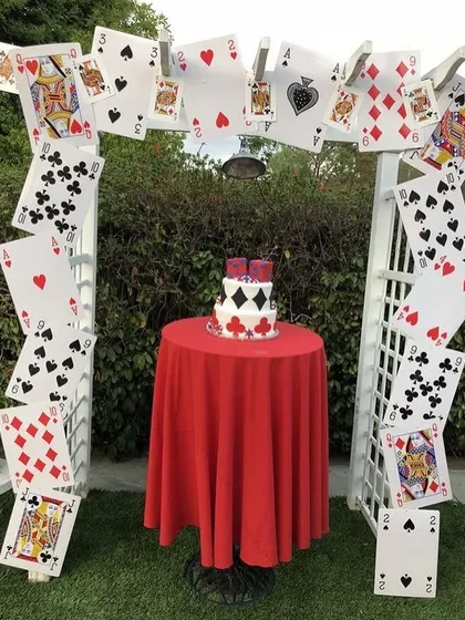 A creative and playful cards-themed party arch. I used a white garden trellis and decorated it with oversized playing cards to create a unique photo spot and cake display area.