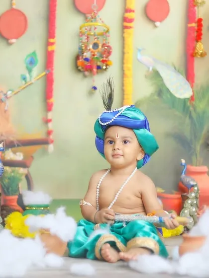 A sweet portrait of a baby boy dressed as Balram, with his flute and serene expression.