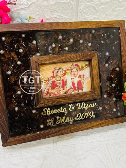 An 8x10 inch teakwood frame with a dark, glittery resin background and preserved flowers. The central photo is in a smaller wooden frame, creating a frame-within-a-frame effect.