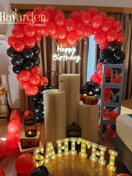 A heart-shaped balloon arch in red and black, perfect for a romantic birthday or anniversary surprise at home.