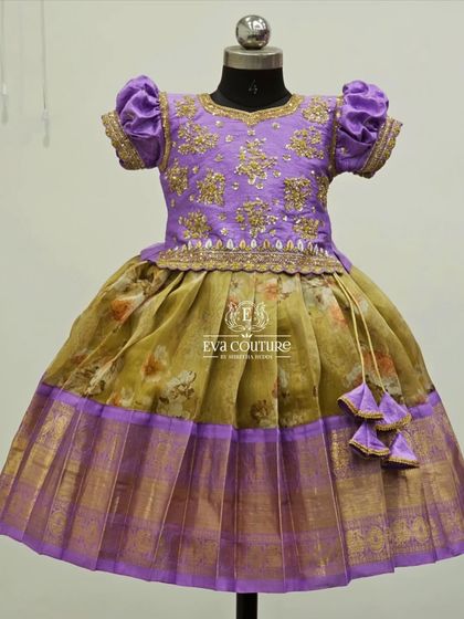 A soft lavender and mustard yellow combination. This Pattu Pavadai has a floral printed skirt and a blouse with delicate gold embroidery.