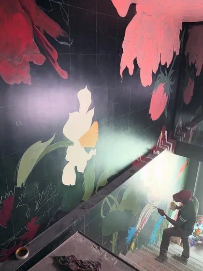 An early stage of the 'Big Flowers' mural, where the composition is being laid out on the dark background. This process shot reveals the careful planning required to create such a large and complex piece.