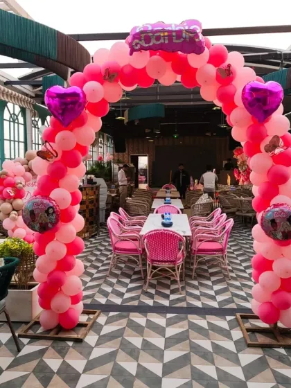 A large Barbie-themed balloon arch at a rooftop restaurant. The arch is made of various shades of pink balloons and is perfect for creating a grand entrance.