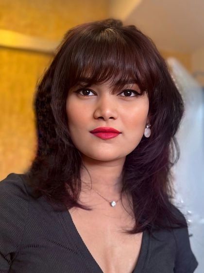 A direct portrait showcasing the autumn-hued hair and modern shag haircut with a full fringe.