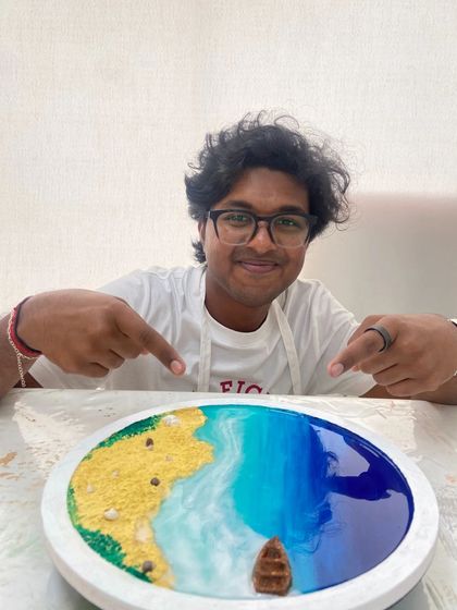 A participant proudly points to his finished resin beach art, happy with the result of his creative efforts.