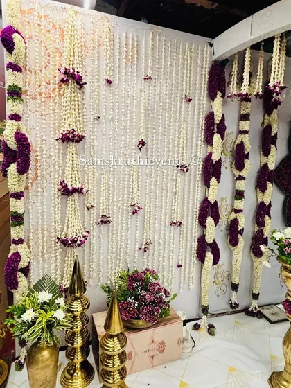 A corner detail of a traditional stage, showing hanging jasmine garlands and ornate golden decor pieces. Every part of the setup is designed with care.