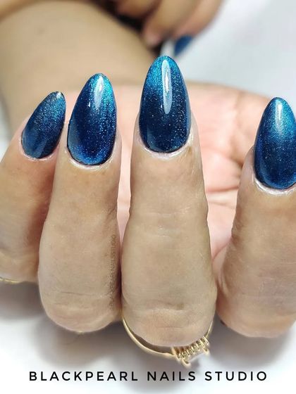 A beautiful example of a silver cat eye base with a blue transparent gel polish overlay. This technique creates a deep, shimmering blue effect that looks like a galaxy on your nails.