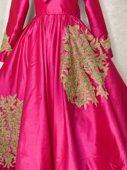 The intricate gold embroidery on the magenta gown adds a touch of royal elegance, making it a truly special piece.