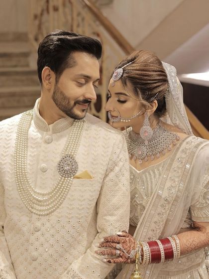 A classic couple portrait. The bride and groom look perfectly coordinated in their white outfits, and her makeup is timeless and elegant.