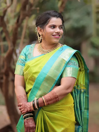 A classic pose for a classic bride. Her makeup features a soft, neutral palette with a pop of color on the lips, perfectly matching her lime green and turquoise saree.