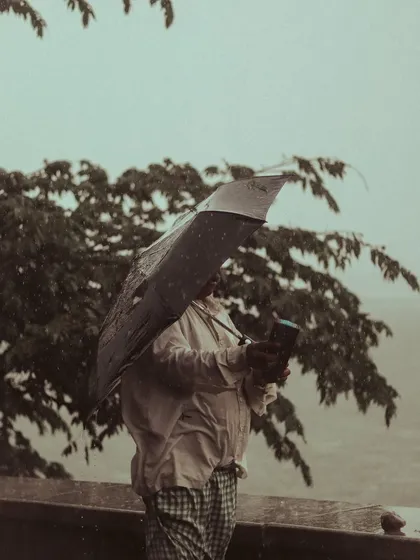A man struggles with his umbrella against the wind at the Powai lakeside. It's a candid, real moment that tells a story of the Mumbai monsoon.
