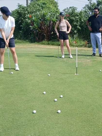 A coach observes as a new player practices her putting stroke. Our workshops offer personalized attention to help you grasp the fundamentals of the short game.