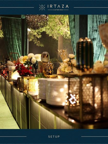 A long shot of a buffet counter at a large wedding event. The setup features dramatic green draping, chandeliers, and a beautifully lit food station, demonstrating how I integrate my catering with the overall event decor.