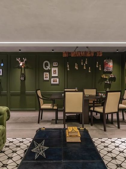 The entertainment room is designed for fun and relaxation. It features a sleek poker table, an emerald-green Chesterfield sofa, and unique decor like designer trunks and a transformer figurine.