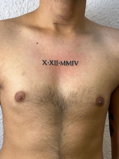 A birthdate in Roman numerals tattooed on the chest. This is a popular and classic way to mark a significant date, placed right over the heart.