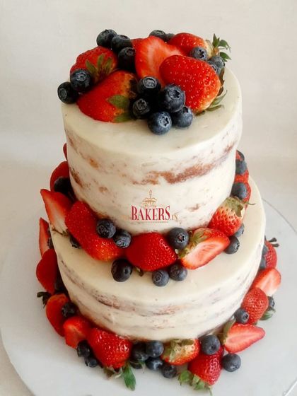 Naked cakes are one of my favorite styles. This two-tier version, with minimal frosting and layered with fresh strawberries and blueberries, was for a 25th-anniversary celebration. The top tier was vanilla with strawberry preserve, and the bottom was vanilla with dark chocolate ganache.