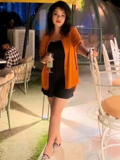 A black romper with an orange shirt, perfect for a stylish evening on a rooftop patio.