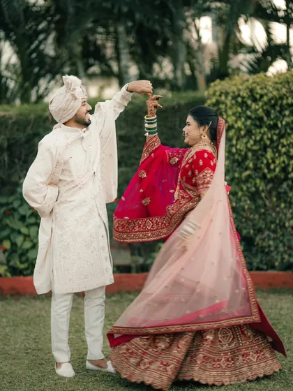 A playful and romantic dance in the garden. The groom twirls his bride, her red lehenga creating a beautiful splash of color.