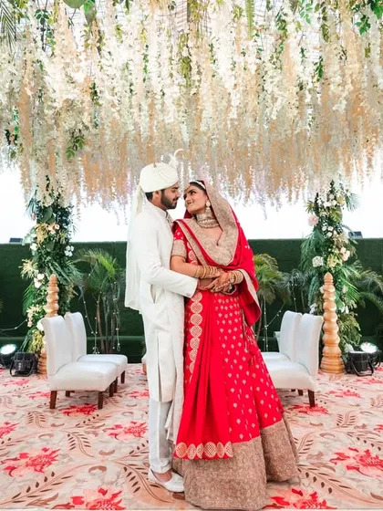 A romantic embrace under the floral mandap. This wide shot captures the grandeur of the decor and the intimacy of the couple.
