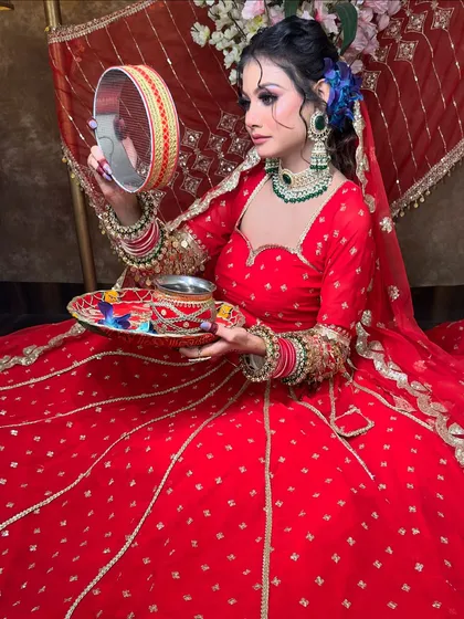 A beautiful shot of the red Karwa Chauth lehenga, showing the traditional sieve (chhalni). The green jewellery provides a lovely contrast against the red fabric.