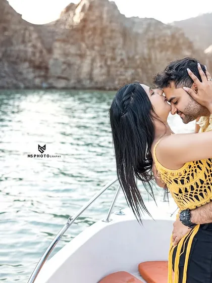 A close-up, passionate kiss on a boat. This image focuses purely on the couple's connection, with the beautiful lake and mountains creating a perfect natural background.