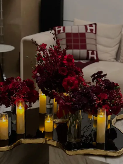 For a luxurious home birthday, we created a dramatic atmosphere using masses of crimson flowers and glowing candles on mirrored and metallic surfaces to reflect the light beautifully.