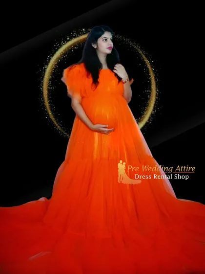 Another look at the vibrant orange ruffled gown in a studio setting. The simple background allows the dress's bold color and full skirt to be the complete focus of the maternity photograph.