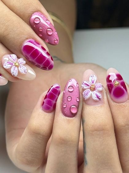 A vibrant and creative 3D nail art set in shades of pink. This design features a crocodile skin texture, sculpted flowers, and realistic water droplet effects.
