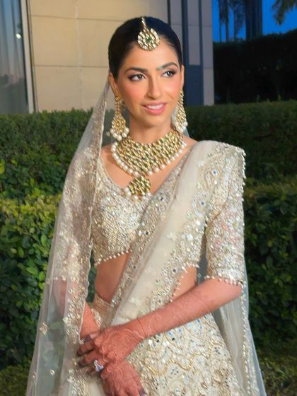 The bride looks ethereal in her white lehenga and sheer veil. Her minimal makeup enhances her natural beauty, proving that sometimes less is truly more for a wedding day look.