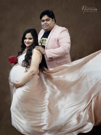 The satin gown catches the light beautifully, creating a soft and glamorous feel. The fabric flows around the couple, adding a touch of drama to this romantic studio portrait.