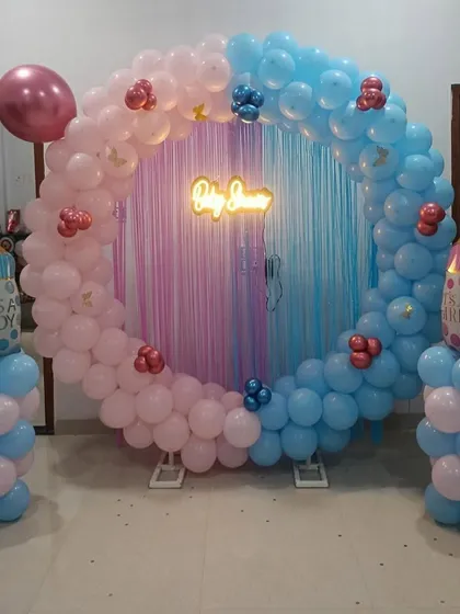 A classic "Boy or Girl" baby shower ring in pink and blue, with baby bottle foil balloons and a neon sign.