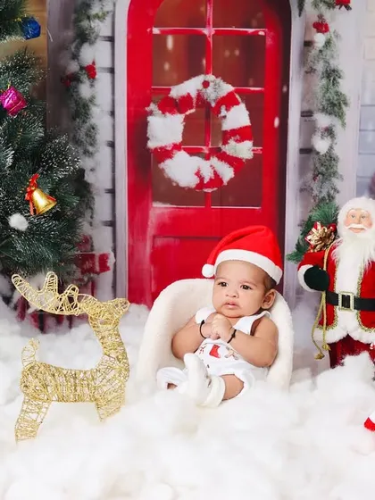 This baby, in a custom Christmas romper, sits patiently for his portrait in the festive winter scene.