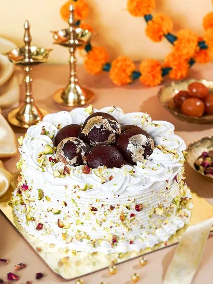 A fusion dessert for Diwali: a cake topped with Gulab Jamuns. The traditional brass lamps and pistachios create a perfect blend of modern baking and Indian tradition.