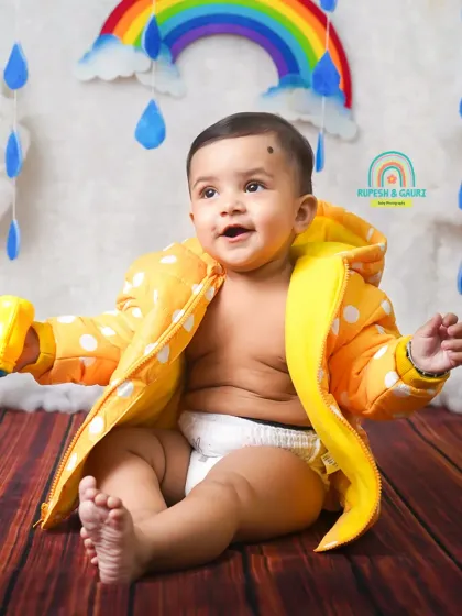 A happy baby enjoying our monsoon theme, complete with a rainbow and fluffy clouds in the background.