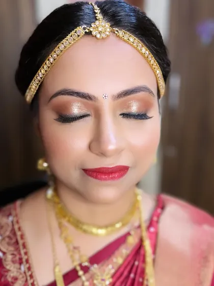 A close-up of the eye makeup for this South Indian bridal look. The shimmering gold and bronze tones make her eyes sparkle, while the bold red lip adds a touch of classic glamour.