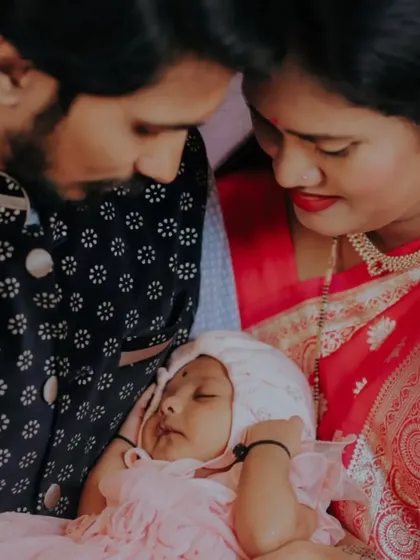 A close-up, intimate portrait of new parents gazing lovingly at their sleeping baby during the naming ceremony.