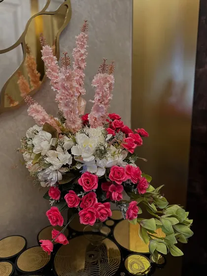 This home wedding decor features a stunning floral installation that flows from a console table and frames a doorway, using a beautiful ombre effect with pink, orange, and white flowers.