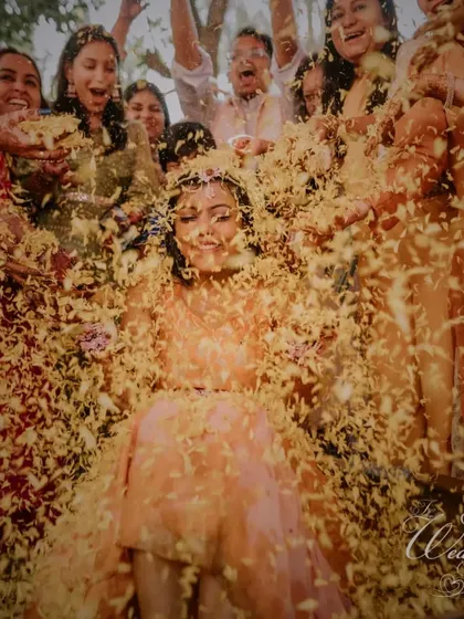 An explosion of flower petals over the bride. This shot perfectly captures the scale and celebratory nature of the Haldi ceremonies I plan.