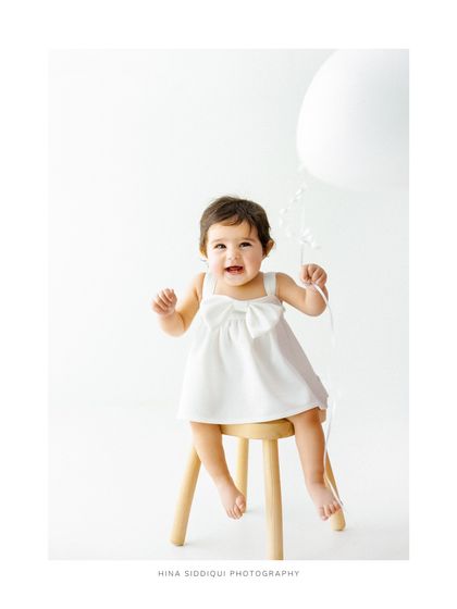 A full portrait version of the joyful balloon moment. The white space in the composition draws the eye directly to her happy face, creating a light and airy feel.