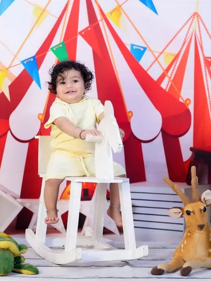 A toddler enjoys a ride on a rocking horse in our colorful carnival-themed setup, perfect for celebrating a first or second birthday.
