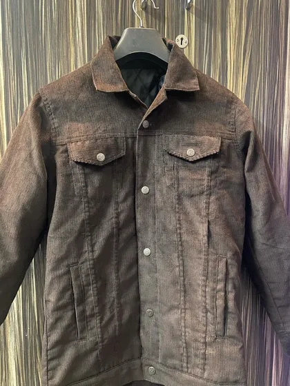 This is a custom-made corduroy jacket in a rich brown, featuring a classic trucker design with flap pockets and a warm, quilted inner lining for extra comfort.