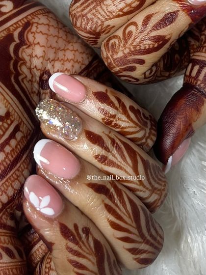 A close up showing the fine details of this bridal nail art. I hand-painted a simple white flower on one nail and added a full silver glitter accent nail, which contrasts beautifully with the classic white French tips.