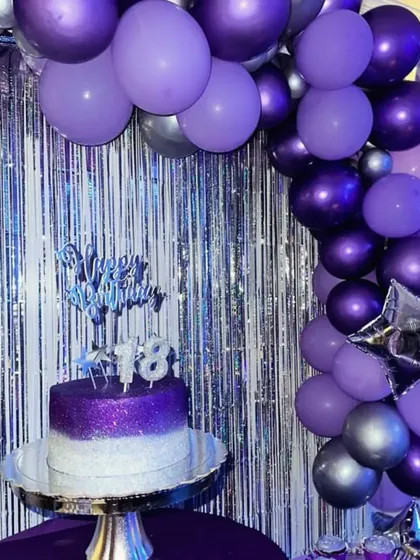 A lovely purple and silver theme for an 18th birthday. The glittery cake, silver fringe backdrop, and metallic balloons are perfect for celebrating this important milestone in style.