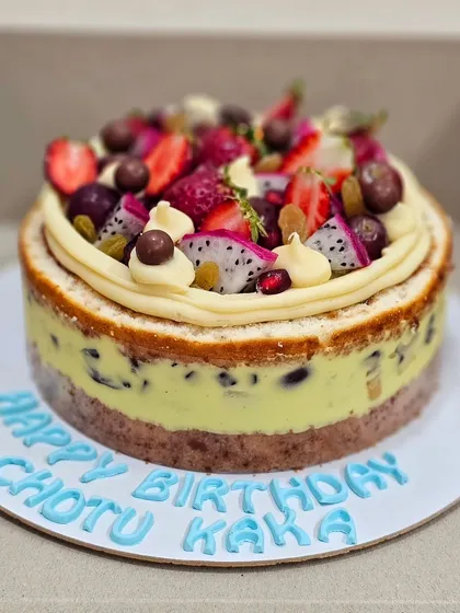A beautiful and fresh Fruit Gateau, a light sponge cake layered with pastry cream and topped with a variety of fresh fruits like dragon fruit, strawberries, and grapes.