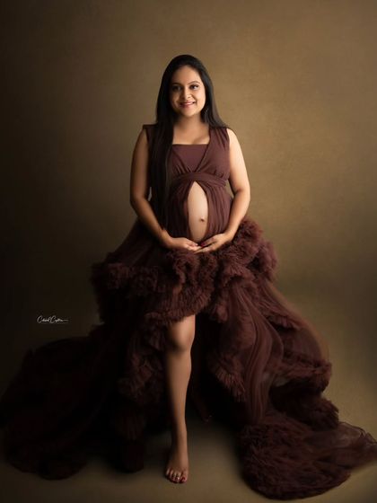 A happy and confident portrait of a mom-to-be in a beautiful, multi-layered brown gown.