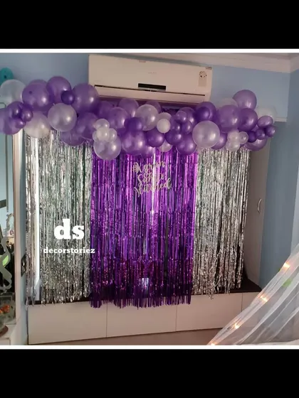 A close-up of the backdrop we created for a room decoration. We used purple and silver foil curtains as a base, topped with a garland of matching balloons to hide the top of the wall unit.