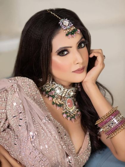 A gorgeous model in a dusty pink lehenga. The makeup is soft and glamorous, with shimmery pink eyeshadow and a matte nude lip.