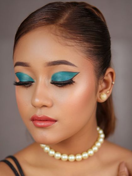A fusion makeup look with a bold, graphic teal winged eyeshadow. Paired with a simple pearl necklace, this look is a perfect blend of modern art and classic elegance.