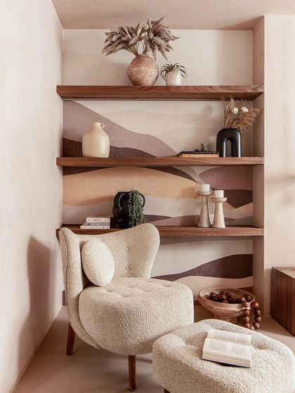 This cozy reading corner in the master suite features a comfortable bouclé chair and custom wallpaper, creating a perfect spot to unwind.