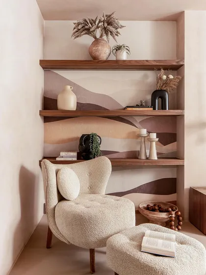 This cozy reading corner in the master suite features a comfortable bouclé chair and custom wallpaper, creating a perfect spot to unwind.